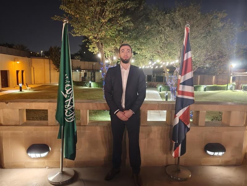 Cassius Edison between the Saudi Arabian and British flags at the UK embassy in Saudi Arabia